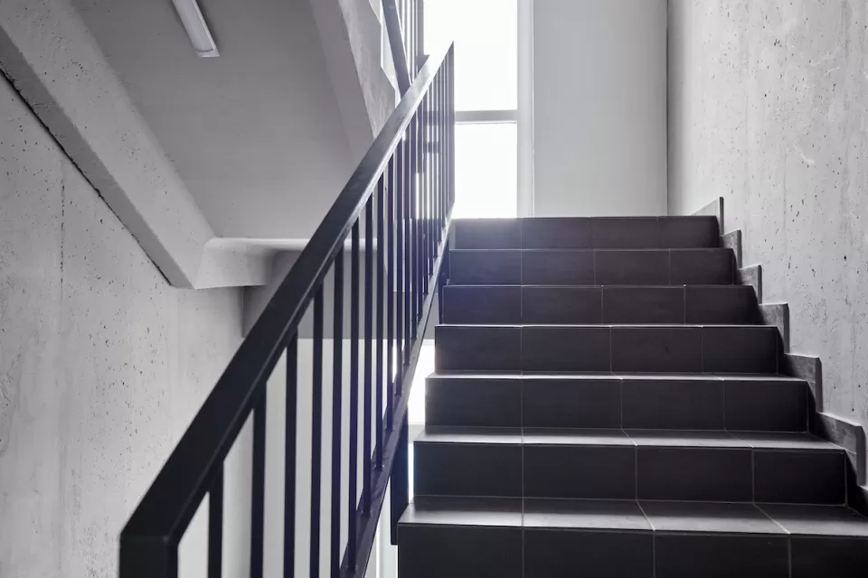 View of plain building staircase with light coming in from window on landing